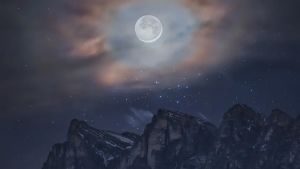 Un’aureola di nuvole circonda la luna sopra le cime delle Dolomiti: ecco lo spettacolare scatto