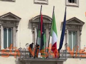 La bandiera libica viene sistemata sul balcone di Palazzo Chigi per la visita del premier Dbeibeh