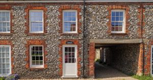 Brick and flint cottage with outbuilding in picturesque village hits the market