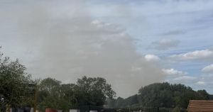 Fire crews tackle blaze as huge plumes of smoke billow from field