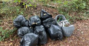 Baby basket and bags of rubbish dumped at entrance to woods